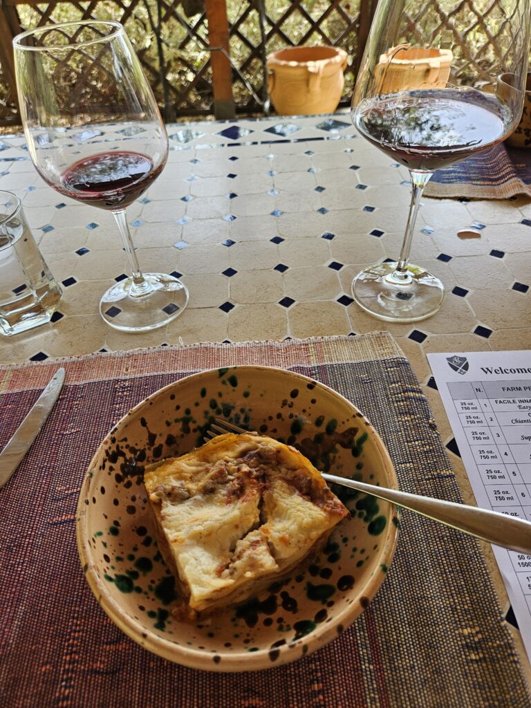 Photo of a bowl of lasagna and half-full red wine glasses.