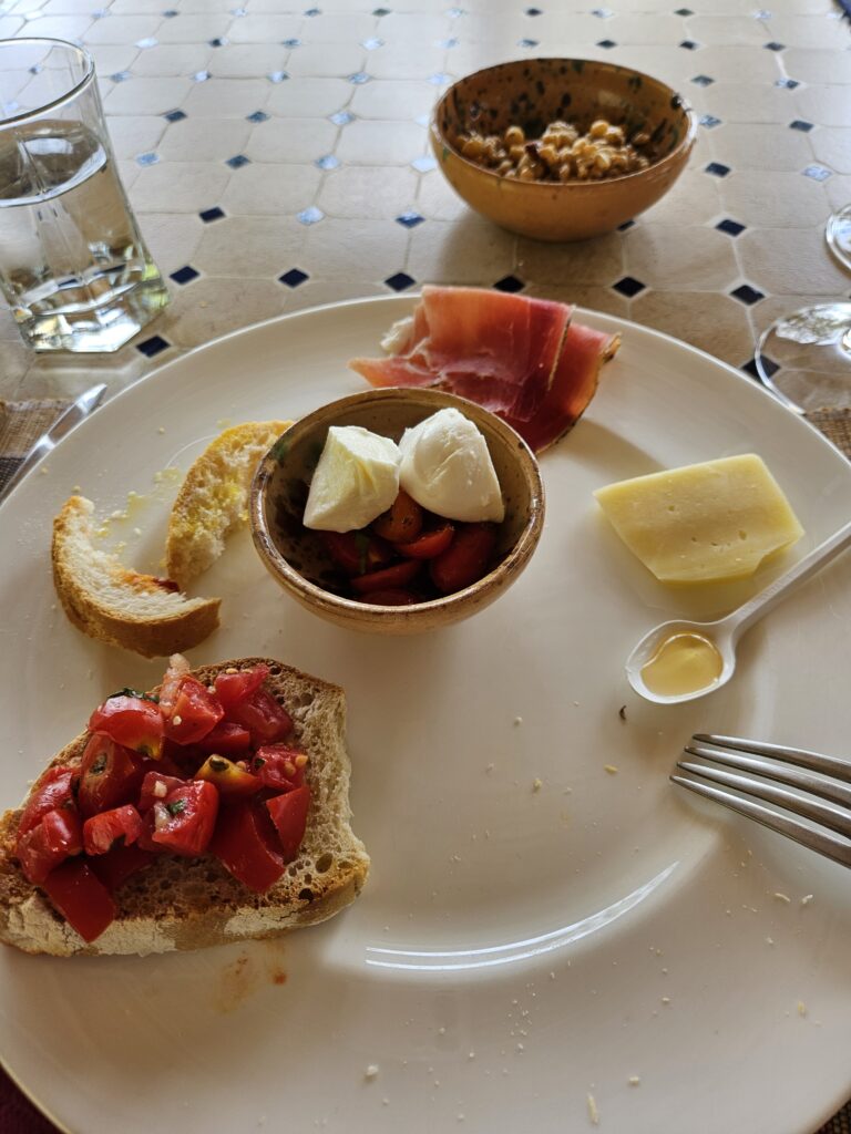 Photo of assorted brad, cheese, tomato, and meats from a vineyard lunch in Tuscany.