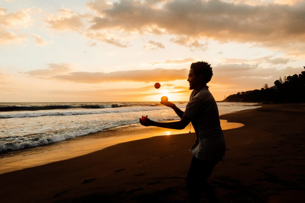 Photo by Rock Staar on Unsplash Man juggling on the beach at sunset to show how people juggle credit scores for Points and Miles Strategies.